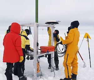 5 people working on sea ice to set up equipment.