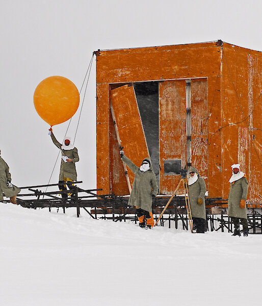 Expeditioners prepare to release a weather balloon on front of the old balloon shed at Wilkes