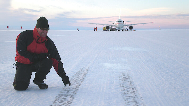 Runway Construction Supervisor pointing out tyre marks on the ice runway — A319 in background.