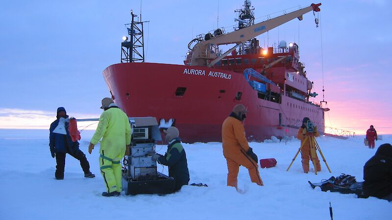 Several scientists working on sea ice in front of the ice breaker, Aurora Australis.