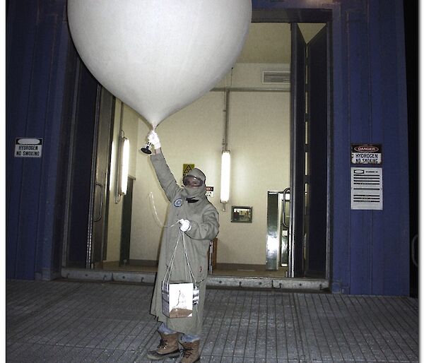 Expeditioner in protective clothing releases ozone sonde (weather balloon)