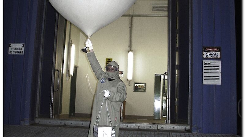 Expeditioner in protective clothing releases ozone sonde (weather balloon)