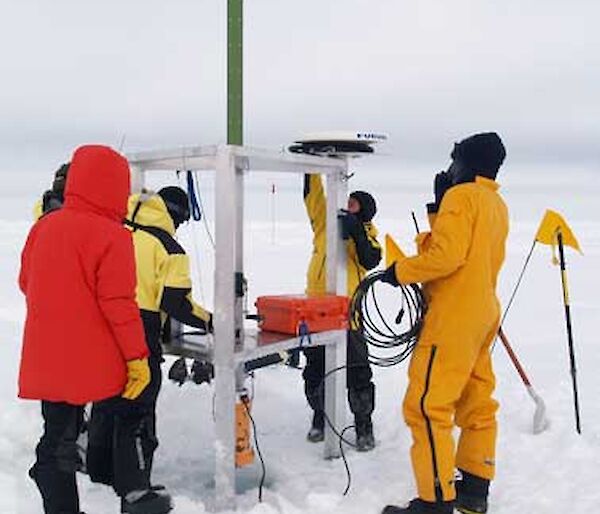 Five people working on sea ice to set up equipment.