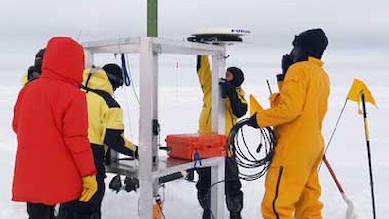 Five people working on sea ice to set up equipment.