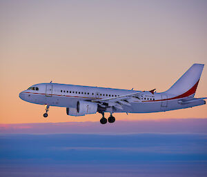 Photo of a plane about to land on an ice runway with a pink sky in the background.