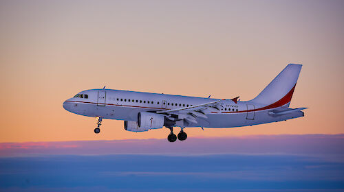 Photo of a plane about to land on an ice runway with a pink sky in the background.