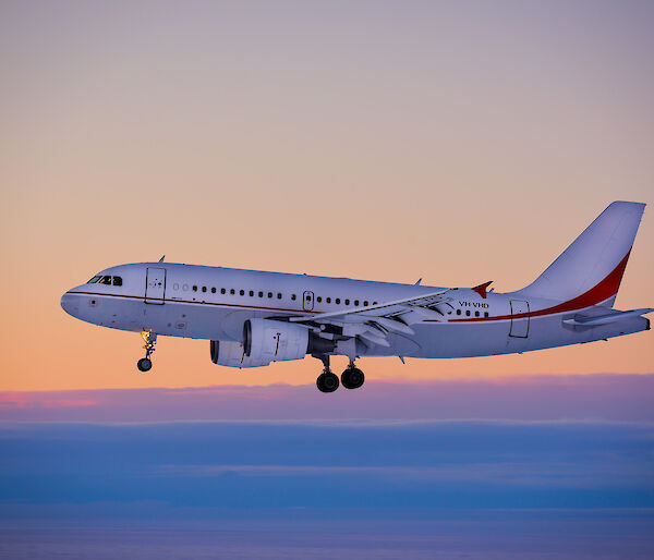 Photo of a plane about to land on an ice runway with a pink sky in the background.