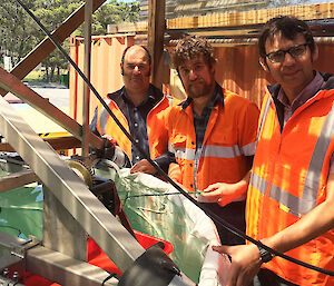 Three men standing around a tank of water.