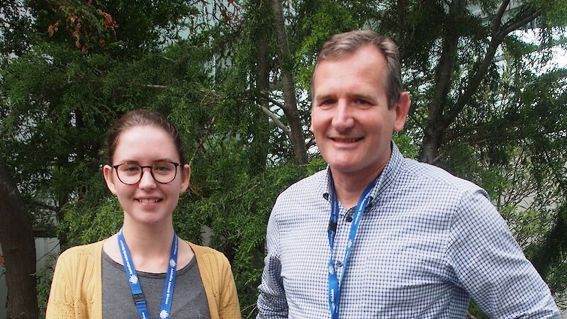 Madeleine and David Rayward standing in front of a pine tree.