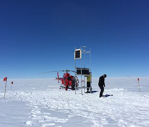 People with a helicopter and instruments on scaffolding on a glacier