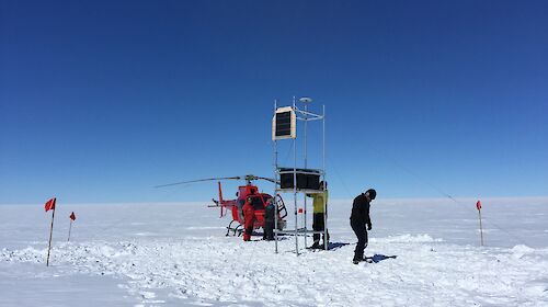 People with a helicopter and instruments on scaffolding on a glacier