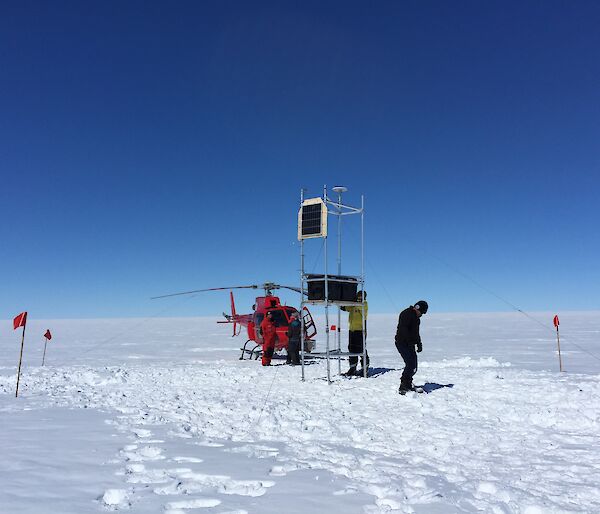 People with a helicopter and instruments on scaffolding on a glacier