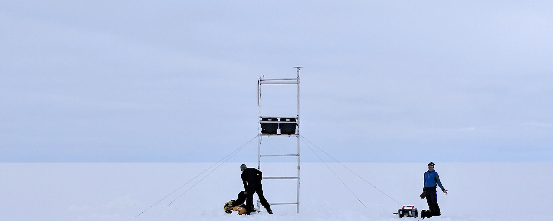 Two sillhouettes of people with instruments on scaffolding on a glacier