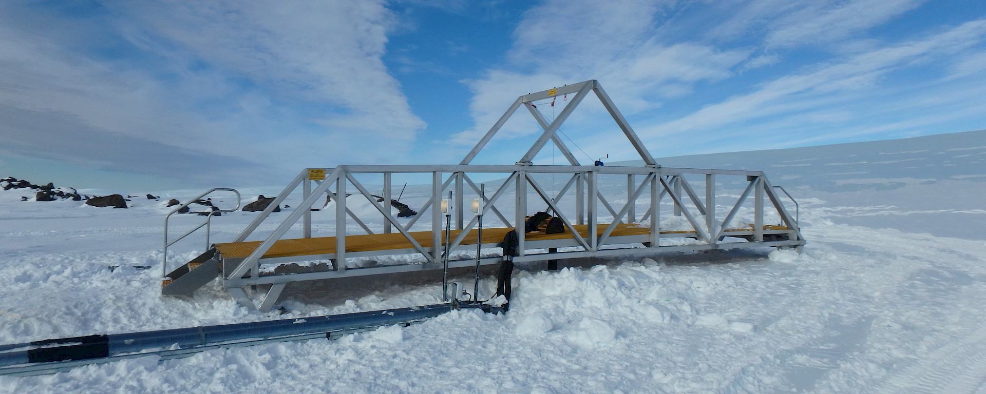 A bridge spanning the 8 metre-wide melt cavern on the Mawson plateau, to allow safe access to the melt bell. Pipework delivering hot water to the melt bell and returning fresh meltwater to the station can be seen in front.