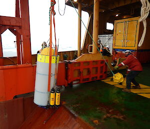 The crew of the Aurora Australis haul a moored acoustic recorder from the Southern Ocean on to the back deck of the ship.