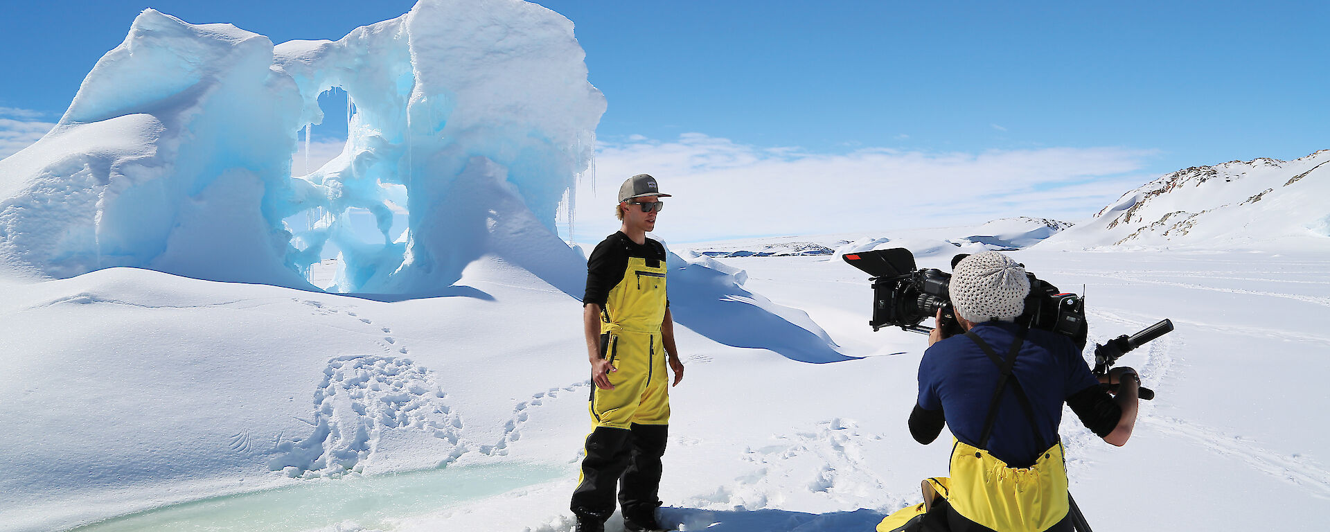Media crew in front of an iceberg in Antarctica