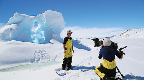Media crew in front of an iceberg in Antarctica