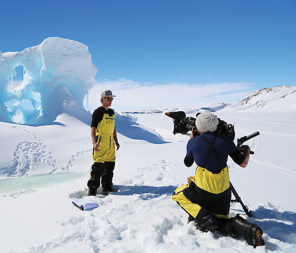 Media crew in front of an iceberg in Antarctica