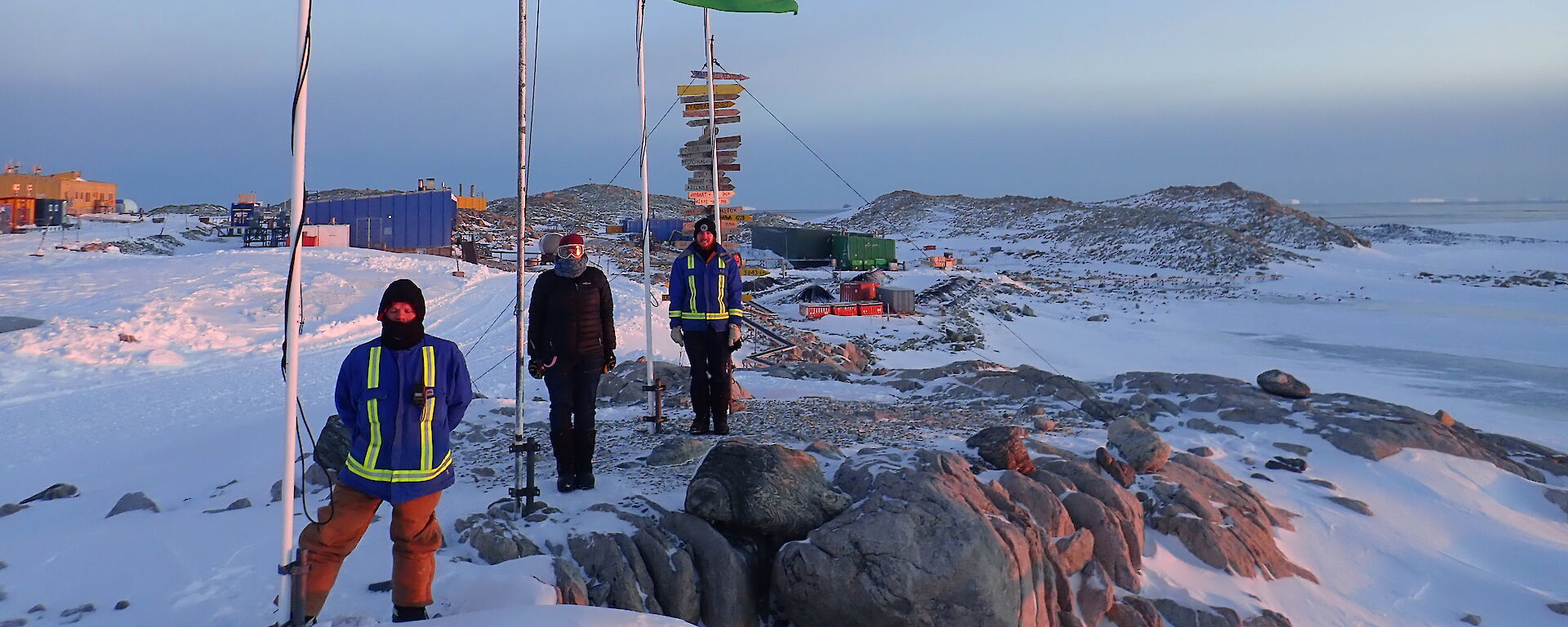 Three people standing under a flag pole with flag flying