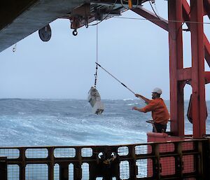 A crew member retrieves the continuous plankton recorder from the ocean off the back of the Aurora Australis.