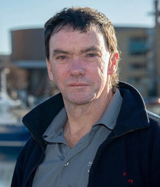 Photo of man standing in front of fishing boats