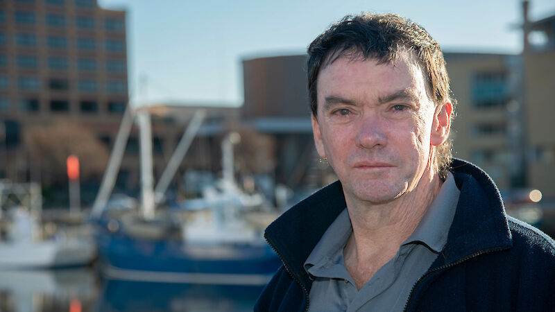 Photo of man standing in front of fishing boats