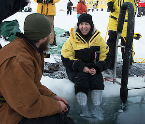 Woman sitting on ice edge with legs in the water