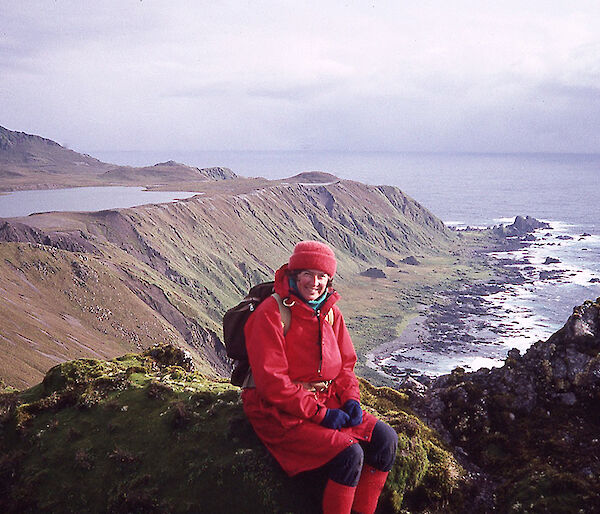 Women sitting on a mountain with island and water behind