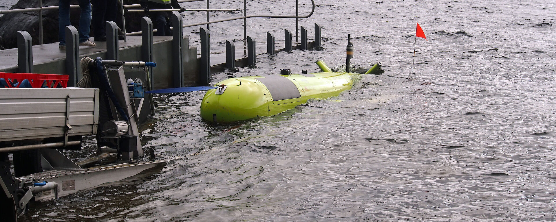 The yellow AUV with a support boat waiting offshore.