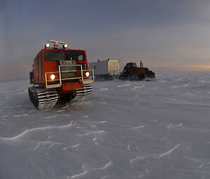 Two tracked vehicles standing idle in the Antarctic twilight