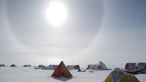Tents pitched on the Antarctic ice sheet with a solar halo in the sky