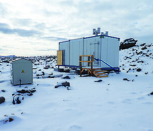 A small building housing the uninterruptible power supply for the infrasound in a snow-covered landscape.
