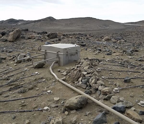 A box containing electronics that collect data sitting on the ground surrounded by small rocks in the Vestfold Hills