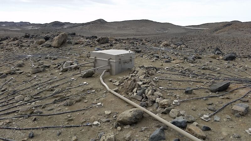 A box containing electronics that collect data sitting on the ground surrounded by small rocks in the Vestfold Hills