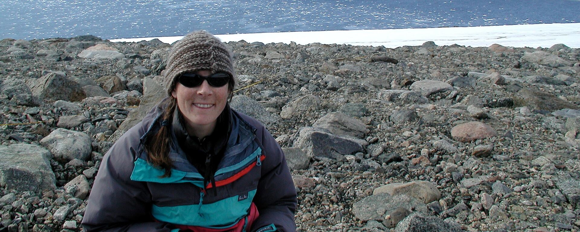 A researcher in a rocky Antarctic landscape taking notes in a field journal.