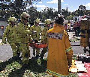 The Casey station fire fighting team carry a stretcher from the fire area