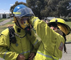 Adjusting the breathing apparatus on an expeditioners head before entering a burning building