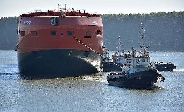 Three tugs position the ship for its return to the wet dock, bow first.