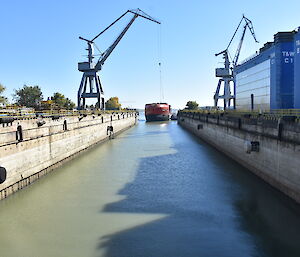 The ship enters the wet dock, pushed by a tug boat from behind.