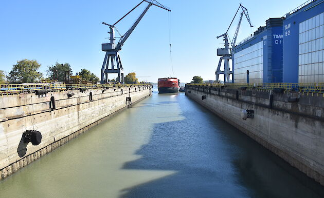 The ship enters the wet dock, pushed by a tug boat from behind.