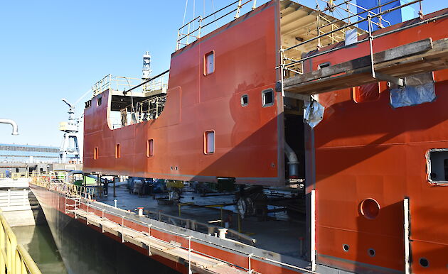 A superstructure block being craned into place above the watertight hull.