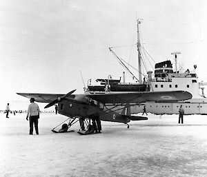 A ski-equipped light aircraft on sea ice in front of a ship