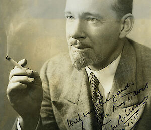 A black and white image of a man with a goatee beard smoking a cigarette