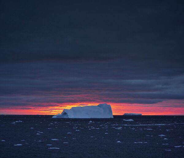 An iceberg against a pink sunset.