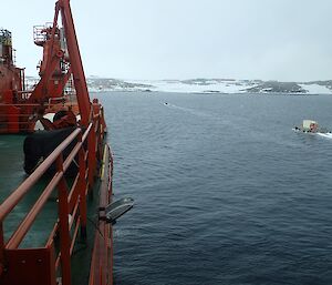 A barge carrying a refrigerated container makes its way from the ship to Casey station.