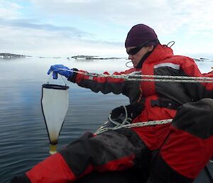 Scientist collecting samples in a small net from over the side of the boat