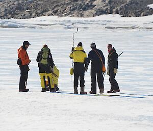 A group of people drilling sea ice to determine whether or not is is safe for travel