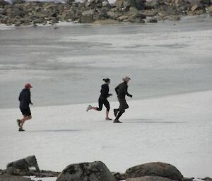 Leading the pack. Three runners on snowy ice.