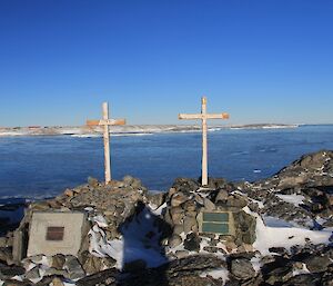 Wilkes graves — original crosses and plaques on rocky outcrops with ice in the background