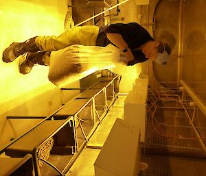 Expeditioner filling tubs with soil under bright lights.